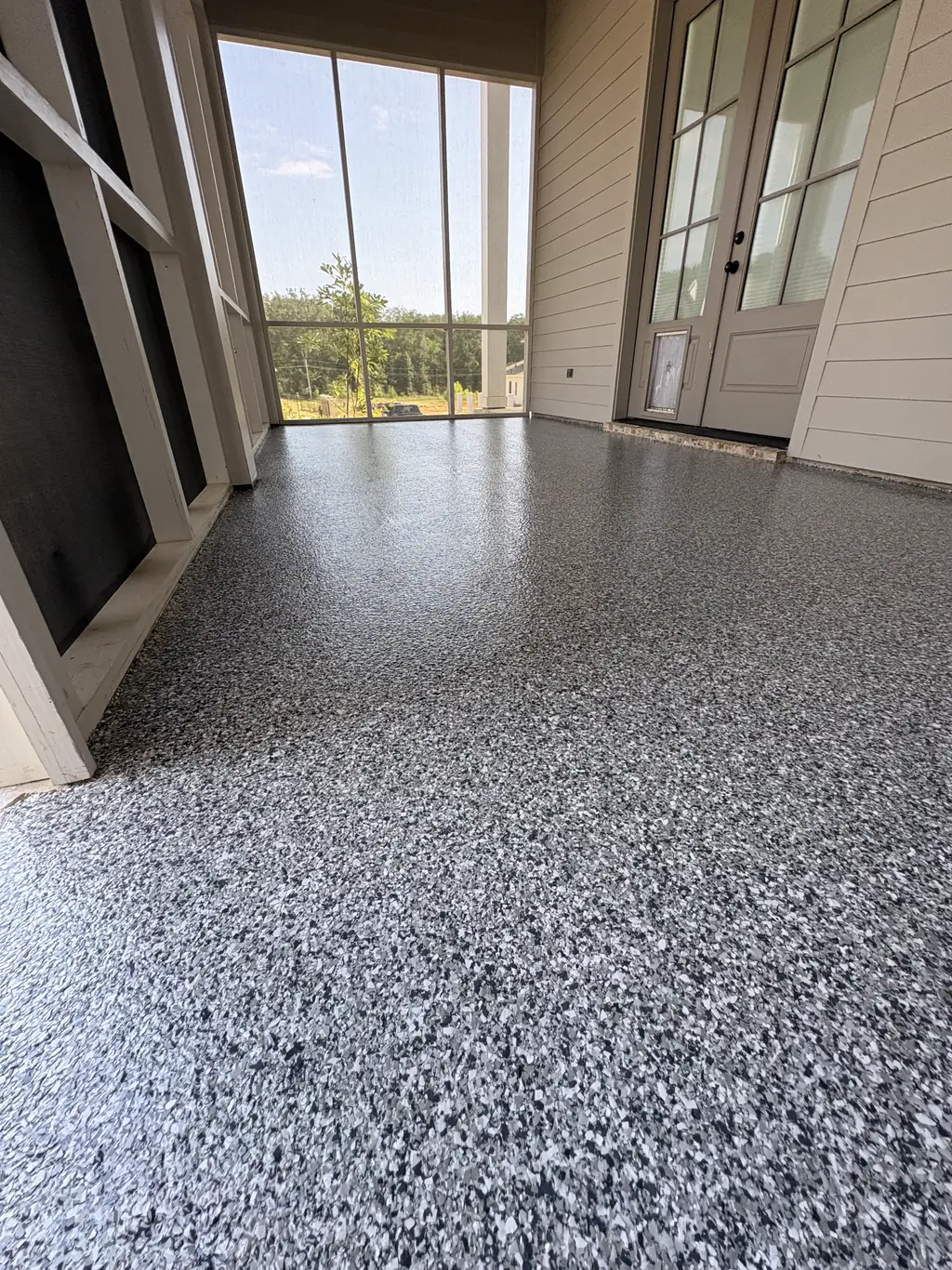 Wide garage bay with a dark gray flake epoxy floor reflecting the doorway